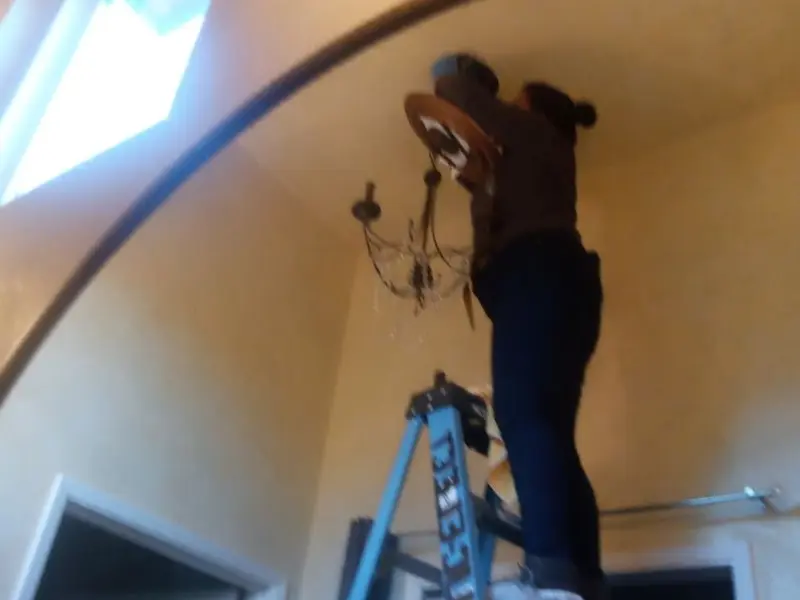 Electrician installing a chandelier in a Corcoran residence